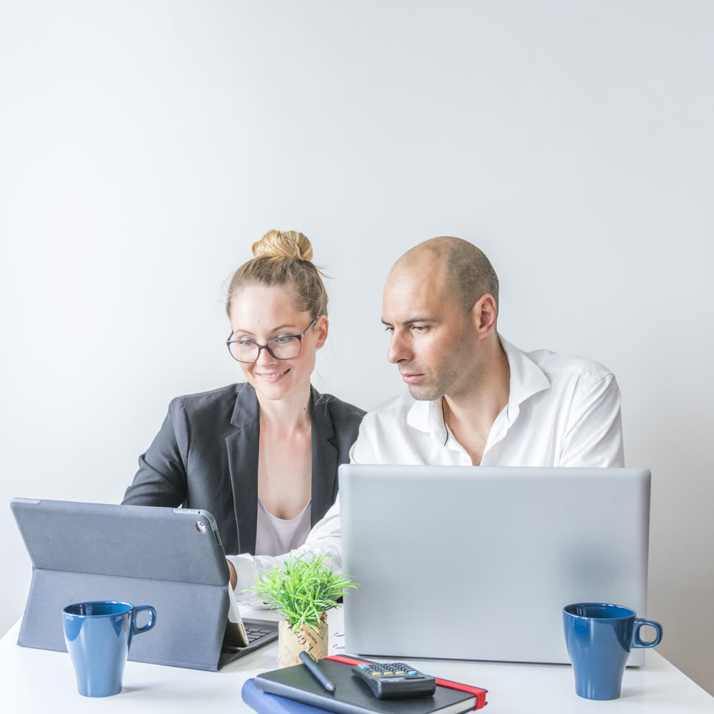 Two colleagues reviewing work on a laptop